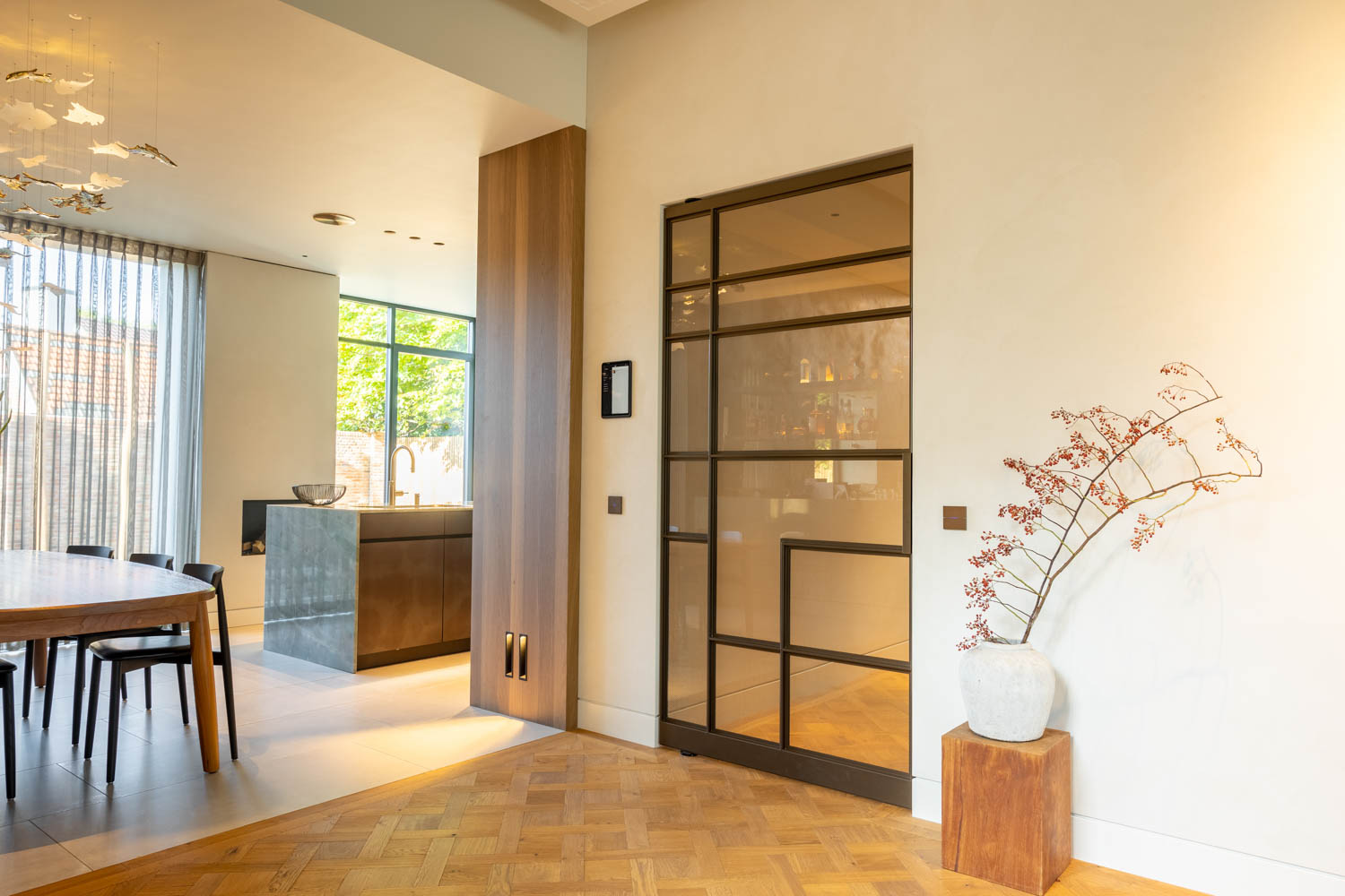 Anodic Brown stalen schuifdeur met glas in een warm interieur met parketvloer en houten accenten.